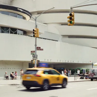 A yellow taxi blurs past the Guggenheim Museum on Fifth Avenue Museum Mile in New York City