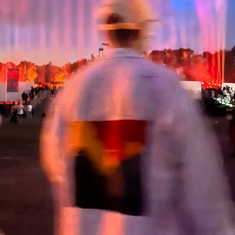 Blurry back of a person wearing a white jacket with red/orange color painting on it