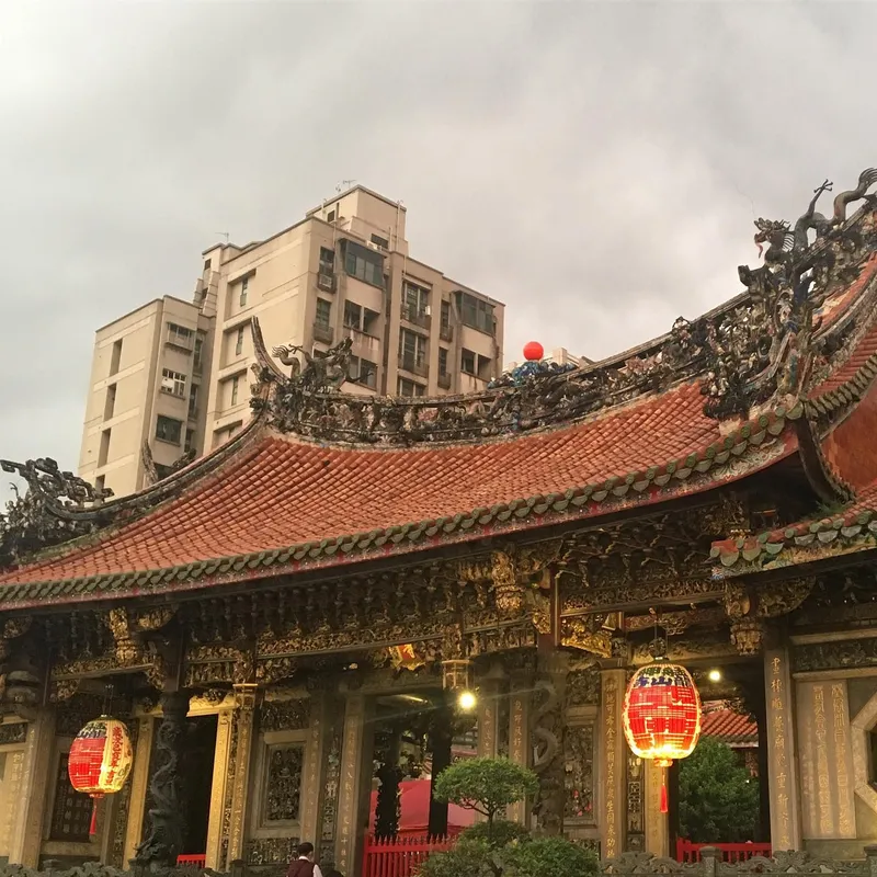 The ornate curved roof of Longshan Temple decorated with dragon sculptures and red lanterns