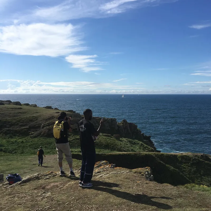 Two people standing on a rocky coastal cliff overlooking the sea