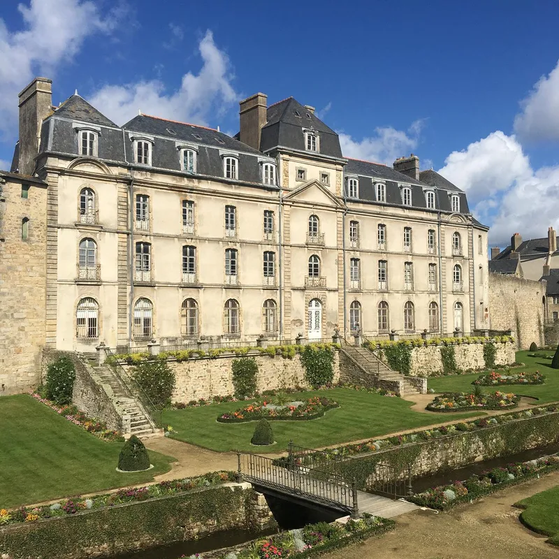 A French château with formal gardens and a small bridge in the foreground