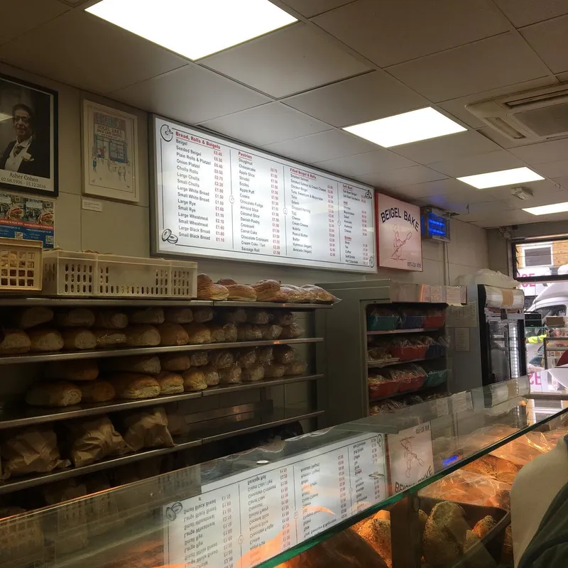 The interior of a bagel shop with shelves of bread and a menu board