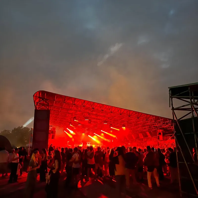 An outdoor festival stage bathed in red light with a crowd in front