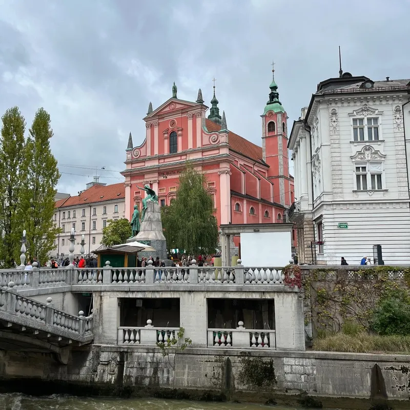 A pink church seen from a bridge over the Ljubljanica river