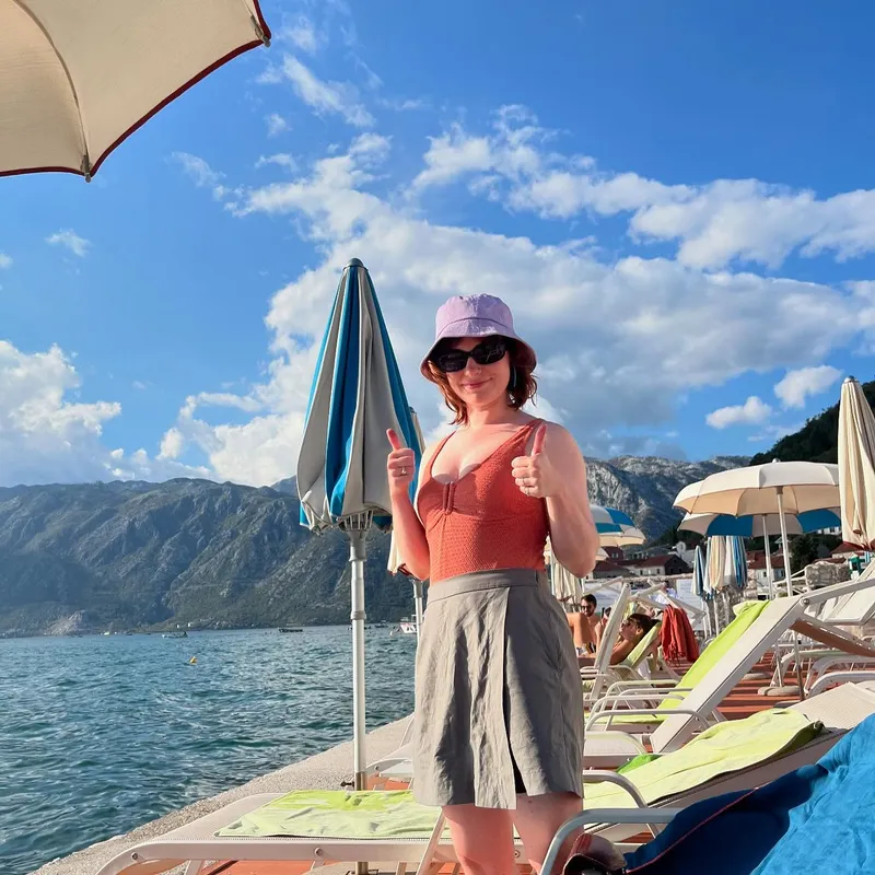 A woman giving a thumbs up with mountains behind her