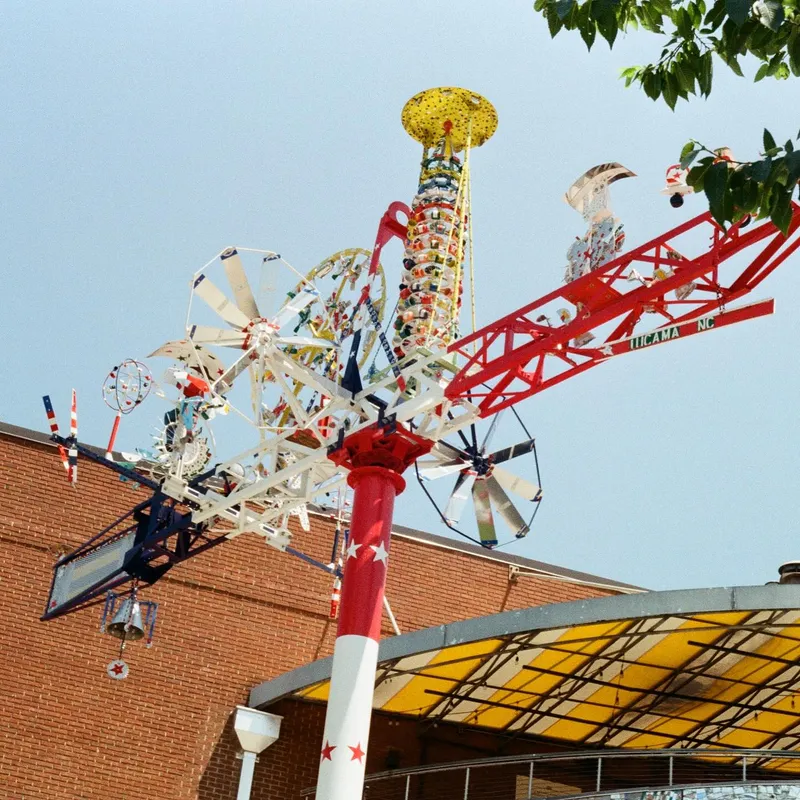 A colorful whirligig folk art sculpture against a blue sky