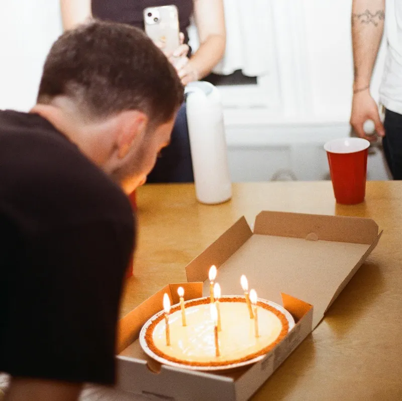 Someone about to blow out candles on a birthday cheesecake