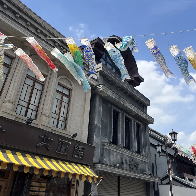 Colorful koinobori carp streamers strung above a traditional Japanese shopping street