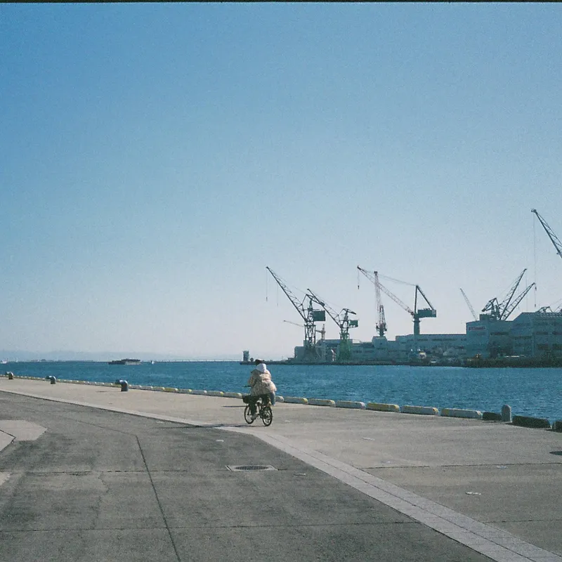 A cyclist riding along a wide concrete pier in Kobe