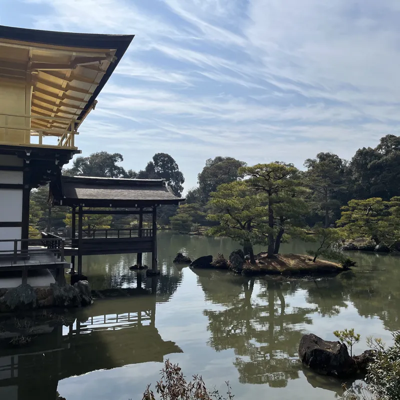 The golden roof of Kinkaku-ji temple reflected in a serene pond with a pine-covered island in Kyoto