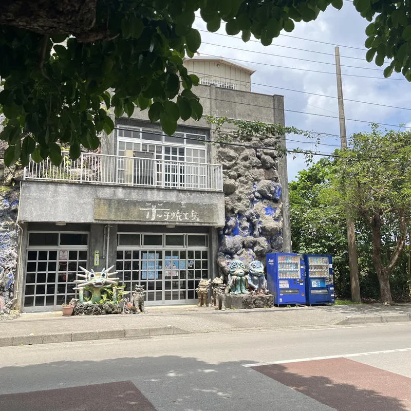 An Okinawan pottery shop exterior decorated with shisa guardian statues and a textured blue mosaic wall